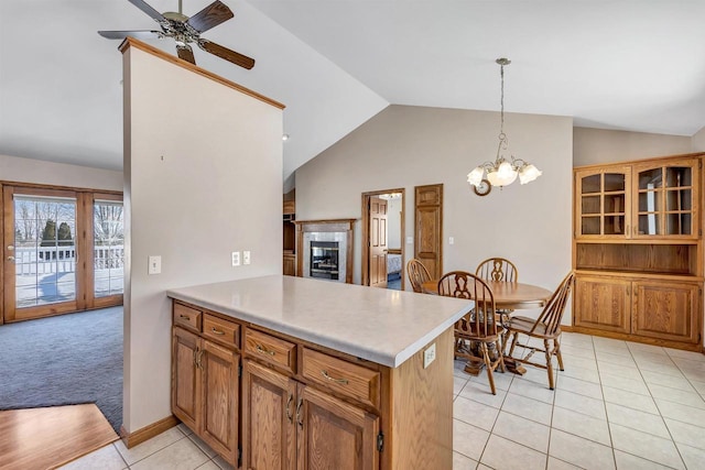 kitchen with a fireplace, kitchen peninsula, decorative light fixtures, vaulted ceiling, and light tile patterned floors