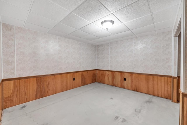 unfurnished room featuring a paneled ceiling and wooden walls