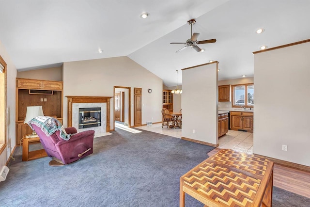 carpeted living room with a fireplace, ceiling fan, sink, and lofted ceiling