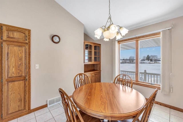 dining space with lofted ceiling, a water view, light tile patterned flooring, and a notable chandelier