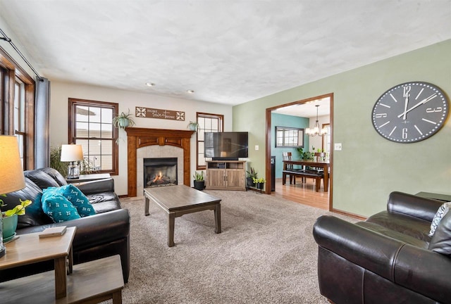 living room with carpet, a chandelier, a healthy amount of sunlight, and a fireplace