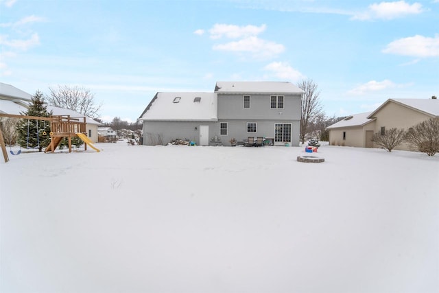 snow covered house featuring a playground