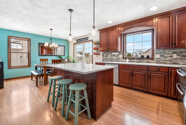 kitchen with backsplash, a center island, pendant lighting, light hardwood / wood-style floors, and stainless steel appliances