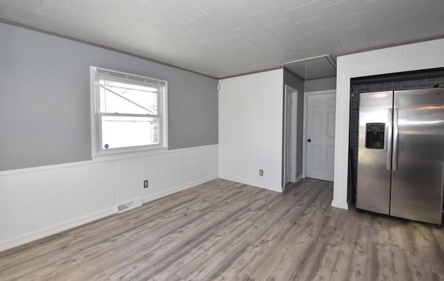 interior space with light wood-type flooring and stainless steel refrigerator with ice dispenser