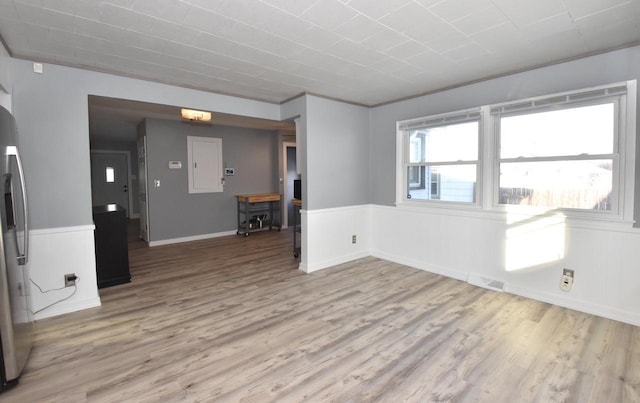 empty room featuring light wood-type flooring and electric panel