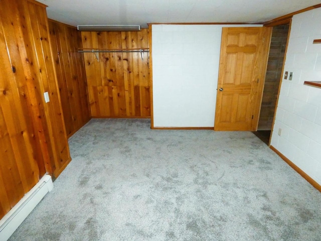 spare room featuring a baseboard heating unit, wooden walls, and light colored carpet