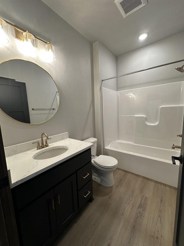 bathroom featuring visible vents, toilet, shower / bath combination, wood finished floors, and vanity