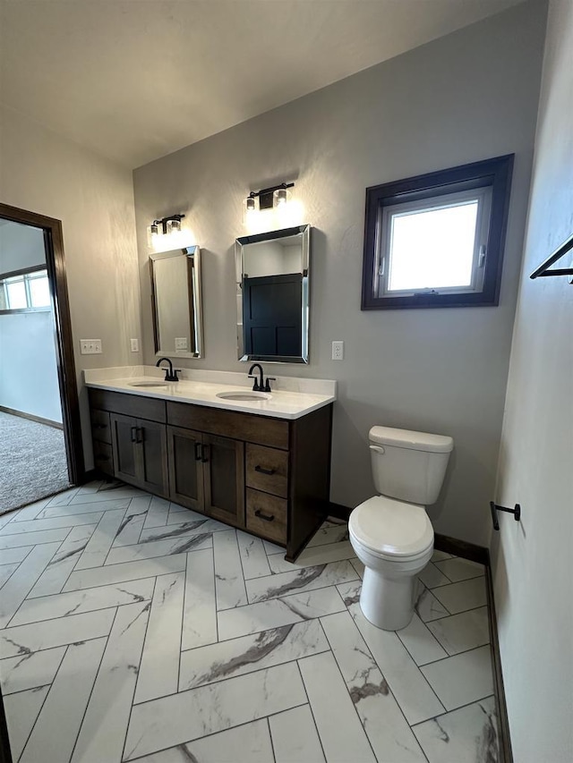 bathroom featuring toilet, baseboards, marble finish floor, and a sink
