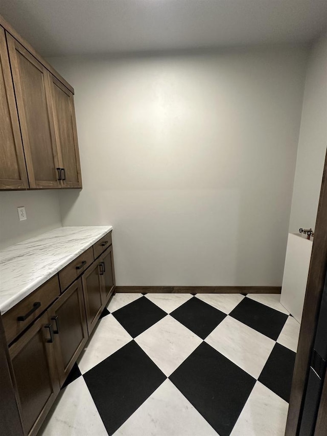 washroom with baseboards and light floors