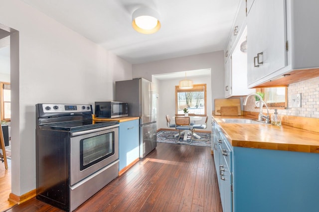 kitchen featuring appliances with stainless steel finishes, sink, wooden counters, dark hardwood / wood-style flooring, and white cabinets