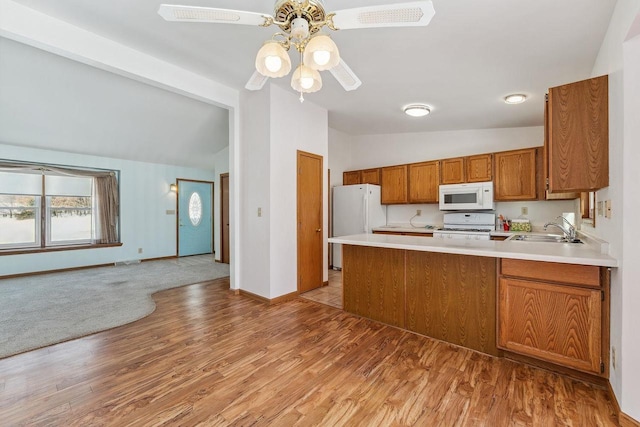 kitchen with light hardwood / wood-style flooring, white appliances, vaulted ceiling, sink, and kitchen peninsula