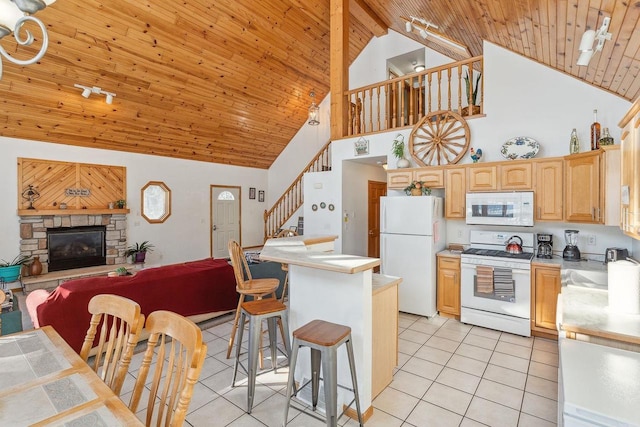 kitchen with white appliances, light brown cabinets, light tile patterned floors, sink, and a kitchen bar