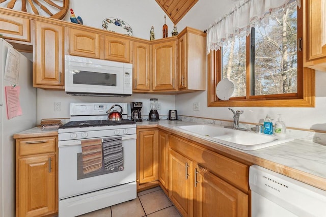 kitchen with white appliances, light tile patterned floors, sink, and lofted ceiling