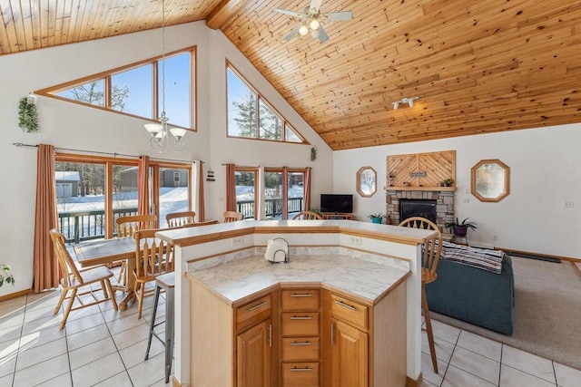 kitchen featuring a fireplace, light tile patterned flooring, a breakfast bar, and wooden ceiling