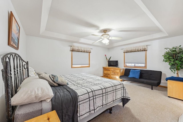 bedroom with carpet floors, ceiling fan, and a raised ceiling