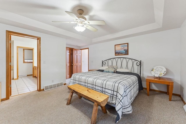 carpeted bedroom with connected bathroom, ceiling fan, and a raised ceiling