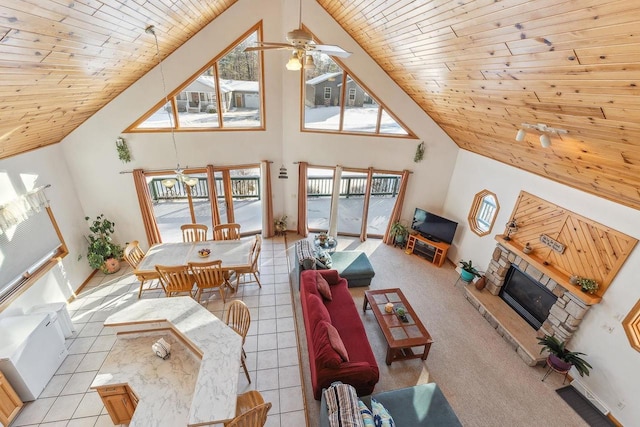 tiled living room featuring high vaulted ceiling, a stone fireplace, and wood ceiling