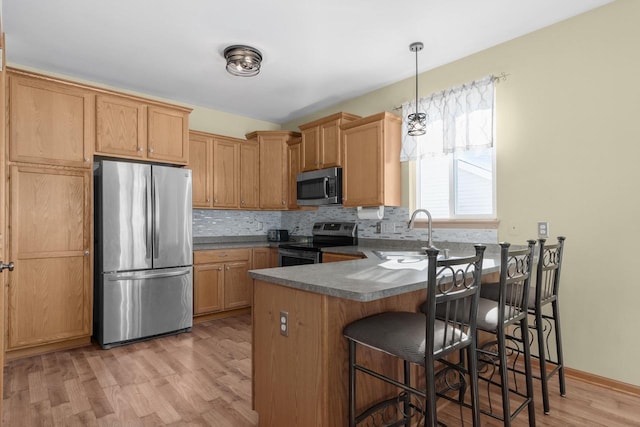 kitchen with sink, decorative light fixtures, light hardwood / wood-style floors, stainless steel appliances, and kitchen peninsula