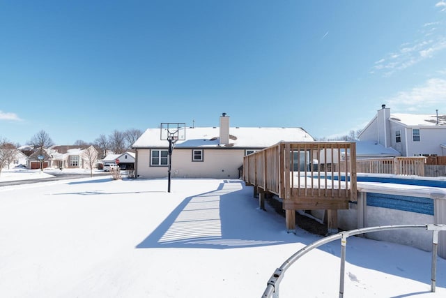 snow covered rear of property with a wooden deck