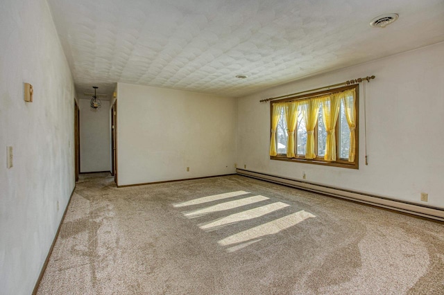 carpeted empty room featuring a baseboard heating unit and a textured ceiling