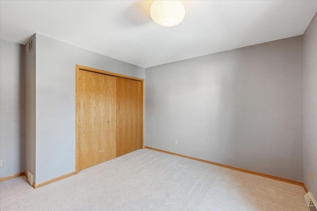 unfurnished bedroom featuring a closet and light colored carpet