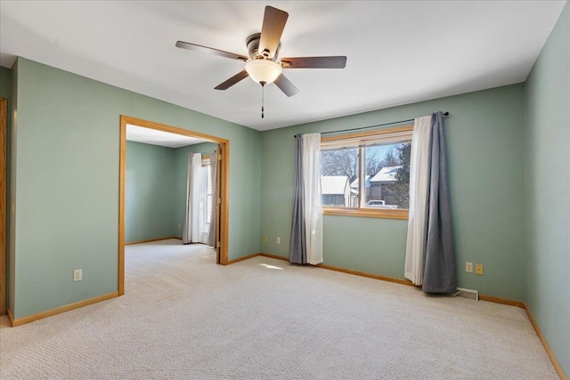 empty room featuring ceiling fan and light carpet