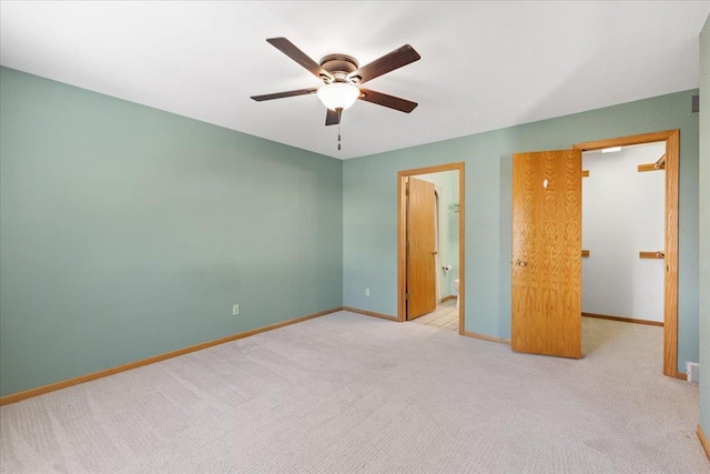 unfurnished bedroom with ceiling fan, light colored carpet, and a spacious closet