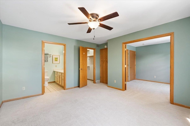 unfurnished bedroom with light colored carpet, a walk in closet, ensuite bath, a closet, and ceiling fan