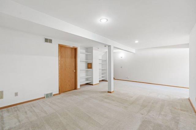 basement featuring light carpet and built in shelves