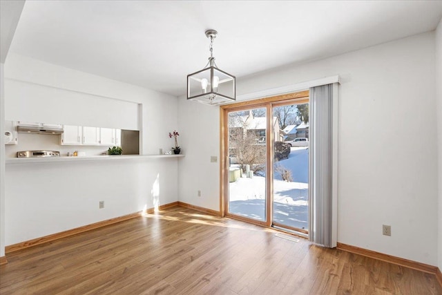 unfurnished dining area with a notable chandelier and light hardwood / wood-style flooring