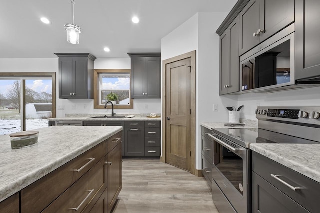 kitchen featuring hanging light fixtures, light wood-type flooring, stainless steel appliances, and sink