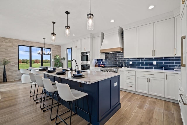 kitchen with custom exhaust hood, hanging light fixtures, and white cabinets