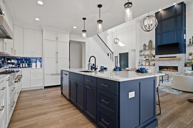 kitchen with sink, pendant lighting, a kitchen island with sink, and white cabinets