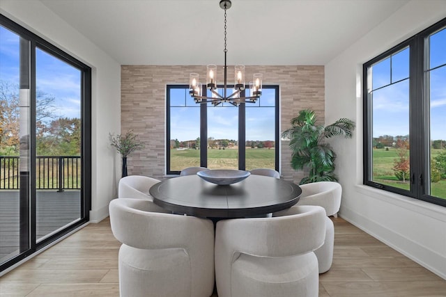 dining room featuring a healthy amount of sunlight, an inviting chandelier, and light hardwood / wood-style flooring