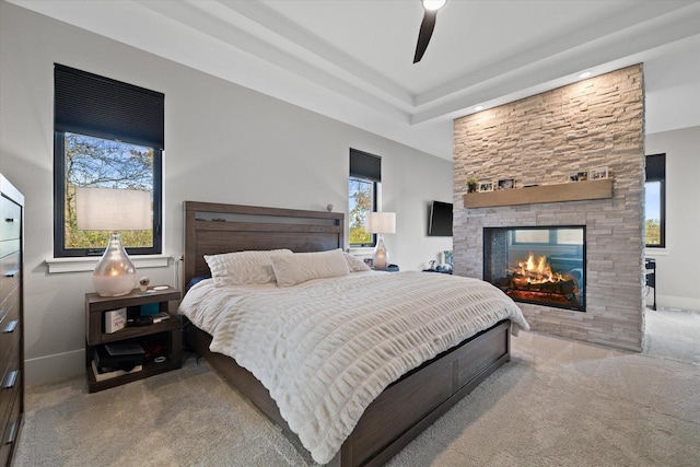 bedroom featuring ceiling fan, multiple windows, a multi sided fireplace, and light colored carpet