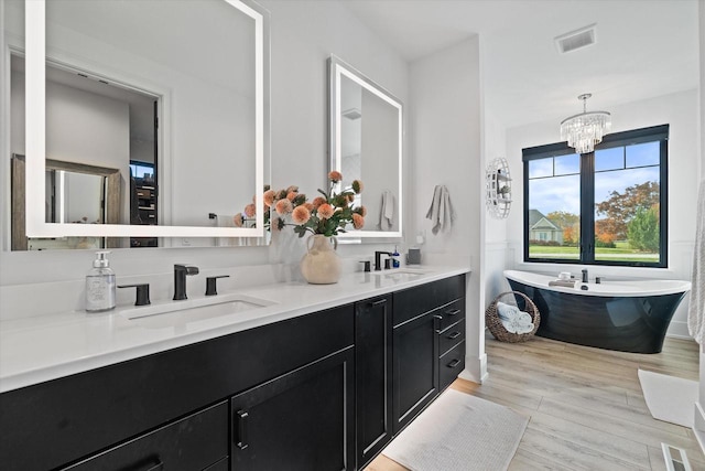 bathroom with a bathing tub, vanity, a chandelier, and wood-type flooring