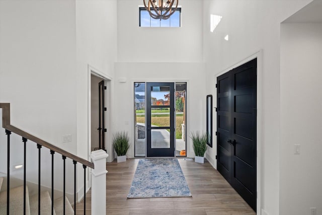 foyer with a towering ceiling, a notable chandelier, and wood-type flooring