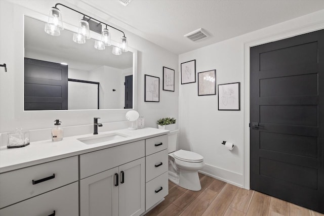 bathroom with toilet, vanity, and wood-type flooring