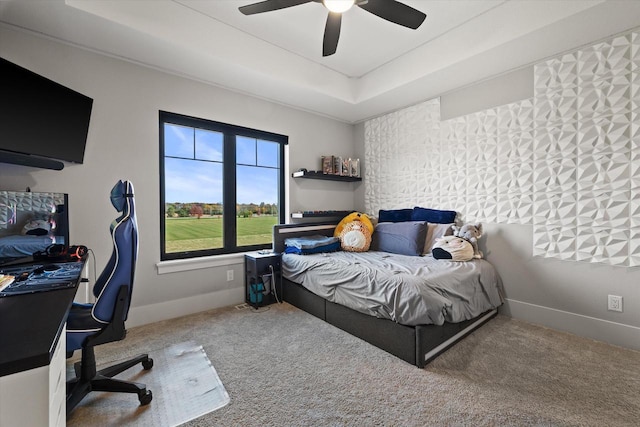 bedroom with a raised ceiling, ceiling fan, and carpet flooring