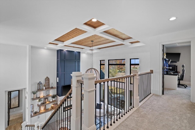 corridor featuring light carpet, coffered ceiling, and beam ceiling