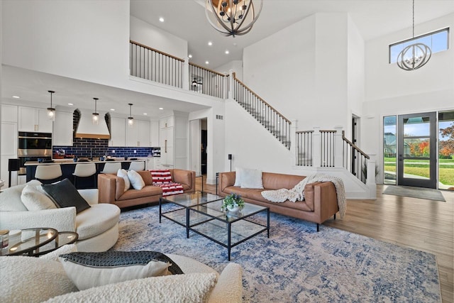 living room featuring light hardwood / wood-style floors, an inviting chandelier, and a high ceiling