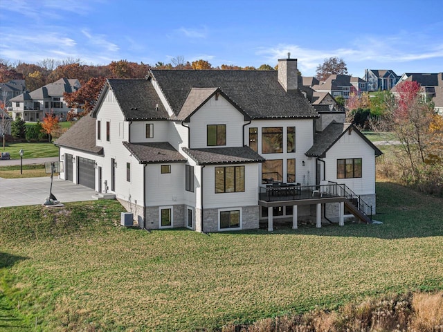 rear view of property with a deck, a garage, and a yard