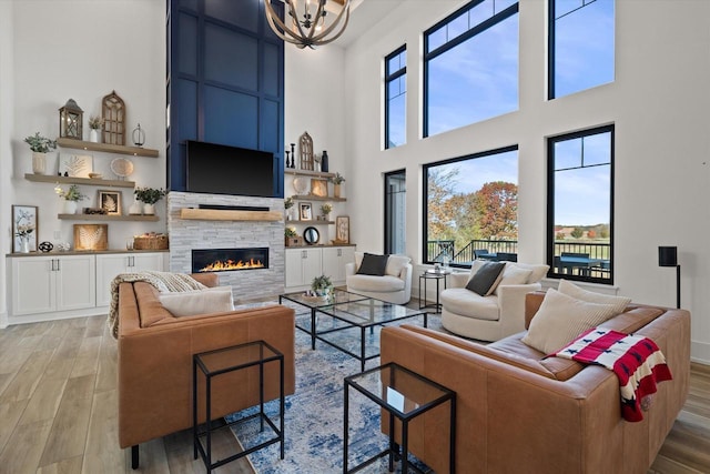 living room with a fireplace, light hardwood / wood-style floors, an inviting chandelier, and a wealth of natural light