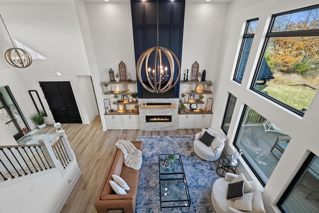 living room featuring a chandelier, light hardwood / wood-style flooring, and a towering ceiling