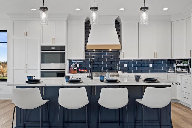 kitchen featuring appliances with stainless steel finishes, white cabinets, a kitchen island with sink, and light stone counters