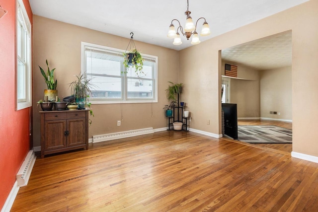 interior space featuring baseboard heating, light wood-type flooring, and a notable chandelier