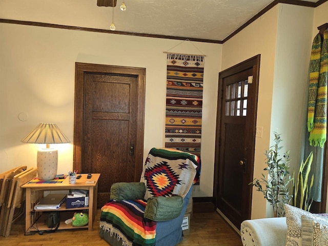 living area with a textured ceiling, crown molding, and wood finished floors