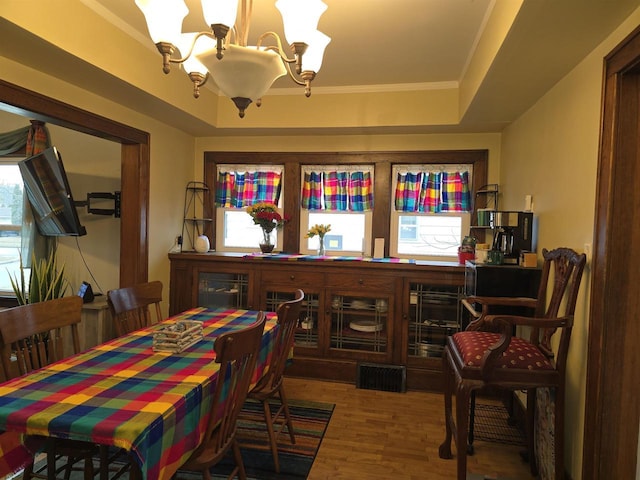 dining area with hardwood / wood-style floors, a wealth of natural light, a tray ceiling, and ornamental molding