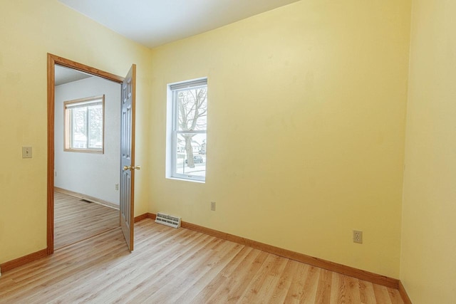 spare room featuring visible vents, light wood-style floors, and a healthy amount of sunlight