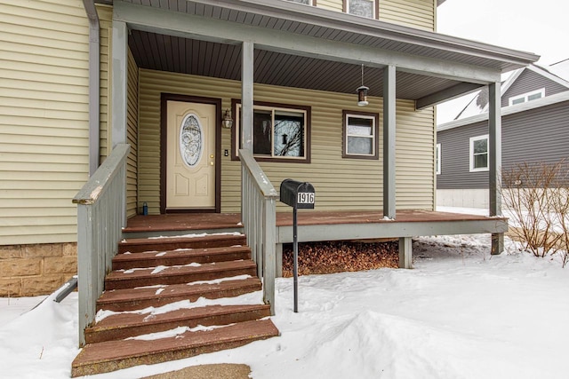 snow covered property entrance with a porch